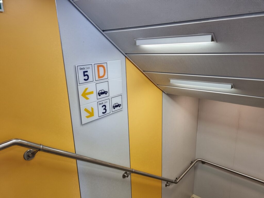 Wegweiser im Treppenhaus der Fähre: Deck 5 mit Restaurant und Shop, Pfeil zu den Fahrzeugdecks