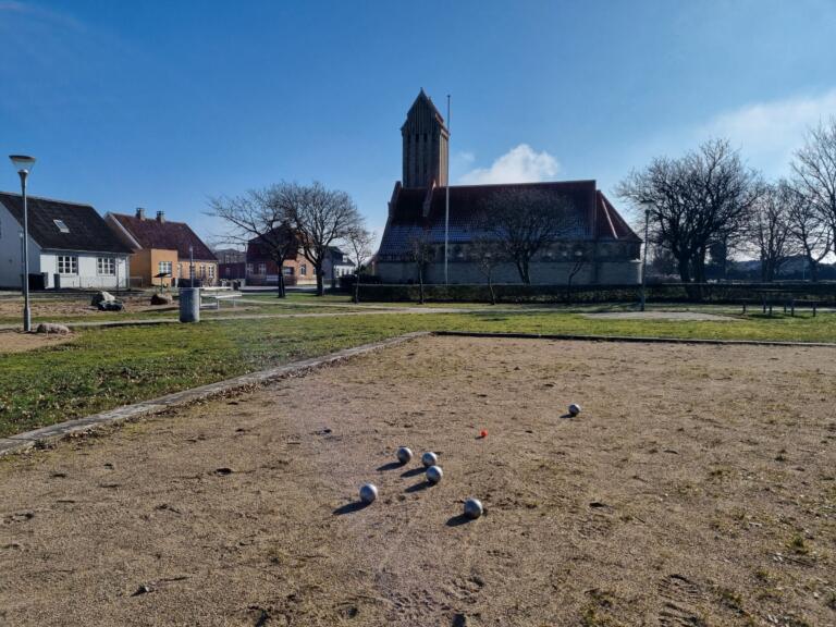 Boule-Platz im Dorf Gedser mit Kirchturm im Hintergrund