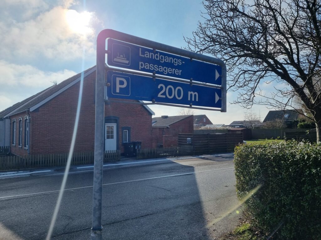 Skilt i Gedser, der viser gående til færgen og en parkeringsplads 200 meter væk