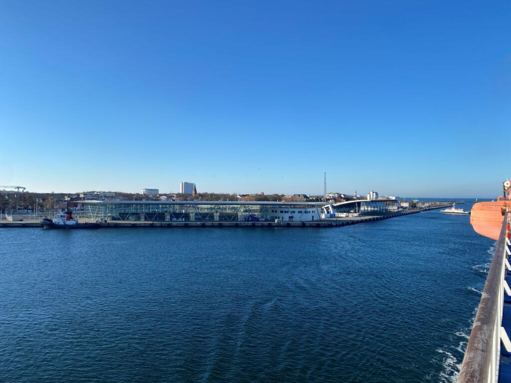 Glazen cruiseterminals aan de kade van Warnemünde met een sleepboot, gezien vanaf het vaarwater