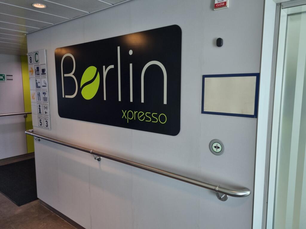 Szyld kawiarni Berlin xpresso na pokładzie 8 obok tablic z numerami pokładów