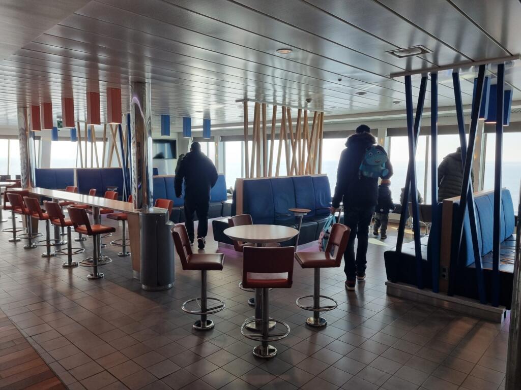 Bar med barstolar och blå soffor ombord med utsikt över havet