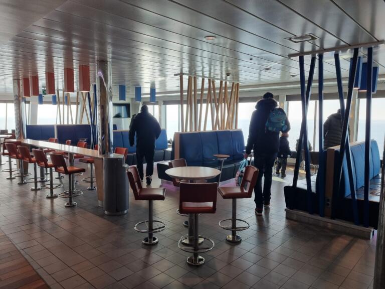 Bar med barstolar och blå soffor ombord med utsikt över havet
