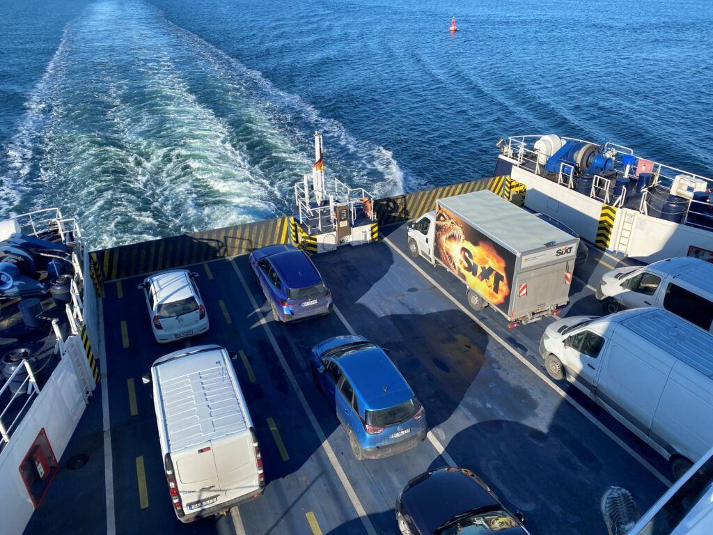 Cars and vans on the open stern deck of the ferry with the wake behind